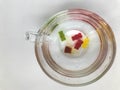 Transparent mug, round and large, filled with water. at the bottom of the mug are gummy bears. bears of yellow, red, green colors