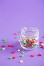 Transparent open glass jar with colorful Christmas sprinkles in