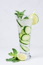 Transparent organic drink with slices cucumber, ice, lime, mint on white wood table. Royalty Free Stock Photo