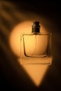 Transparent perfume bottle on an orange background, beautiful shadows artistic photo.