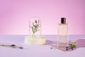 A transparent perfume bottle placed on an acrylic sheet, lavender flowers and props on a pastel purple background. Exquisite space