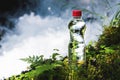 Transparent plastic A bottle of clean water with a red lid stands in the grass and moss on the background of a rugged