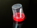 Transparent plastic container with a red lid on a dark background Royalty Free Stock Photo