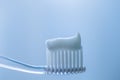 Transparent plastic toothbrush with white toothpaste on a blue white background with reflection on the glass Royalty Free Stock Photo