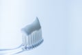 Transparent plastic toothbrush with white toothpaste on a blue white background with reflection on the glass Royalty Free Stock Photo