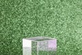 transparent podium for product display on green glittering background.