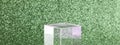 transparent podium for product display on green glittering background.