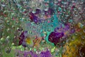 Transparent raindrops falling down against the multi colored background with silhouettes of purple-blue flowers. Royalty Free Stock Photo