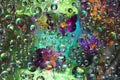 Transparent raindrops falling down against the turquoise-green background with silhouettes of orange-purple flowers. Royalty Free Stock Photo