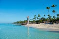 Transparent sea water and clear sky. Lighthouse on a sandy tropical island with palm trees. Royalty Free Stock Photo