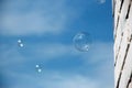 Transparent soap bubble on blue sky with clouds and white brick wall background. On a Sunny summer day. Sky texture. Close up Royalty Free Stock Photo