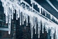 Transparent straight icicles on house on wire on dark background.