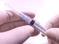 Transparent syringe with closed cap hold by doctor's hand in rubber glove. close up