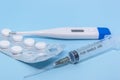 Transparent syringe, white digital electronic thermometer and white tablets in a used blister. medical treatment concept