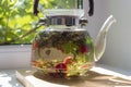 Transparent teapot with green tea and herbals