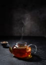 transparent teapot with tea on a dark background