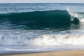 Transparent tourqouise blue wave tube breaking with foam on shoreline with backspray, and backwash Royalty Free Stock Photo