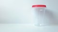 Transparent urine analysis container with a red lid. Clear specimen cup on a white backdrop. Concept of urinalysis Royalty Free Stock Photo