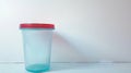 Transparent urine analysis container with a red lid. Clear specimen cup on a white background. Concept of urinalysis