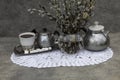 A transparent vase with blossoming willow branches sits on a white lace napkin.