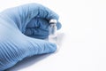 Transparent vial or bottle with the vaccine is in the doctor`s hand, which is dressed in blue medical gloves. The concept of vacci