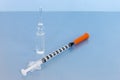 Transparent vial container with liquid medicine near small insulin syringe on blue background. Royalty Free Stock Photo