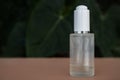 Transparent vial isolated against a blurred background with plants