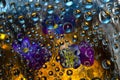 Transparent water droplets falling down against the gold-blue background with purple-blue flowers. Royalty Free Stock Photo