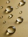Transparent water droplets reflecting light and casting soft shadows on a smooth golden textured surface with varying sizes and Royalty Free Stock Photo