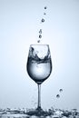 Transparent water pouring into wineglass while standing on the glass with water bubbles against light background. Royalty Free Stock Photo