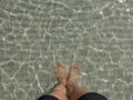 Transparent water ripple, sand waves and sunlight glare. sea floor with people leg and foot stand Royalty Free Stock Photo