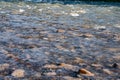 Transparent water in river with rocky bottom, fast flow. Nature outdoors close-up. Sun glare on smooth stones at bottom Royalty Free Stock Photo