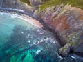 Aerial view of a curvy coastline wih transperant blue water, a thin rocky beach and a cliff Royalty Free Stock Photo