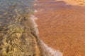 Transparent waves of pure sea waves with foam roll on a golden sandy deserted beach on a sunny day Royalty Free Stock Photo