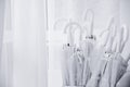 Transparent white umbrellas stored near door of room in stand, waiting for rain