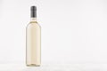 Transparent wine bottle with white wine on white wooden board, mock up.