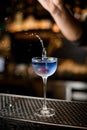 transparent wine glass with splashing blue drink and decorated with white flower on bar counter Royalty Free Stock Photo