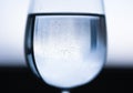 Transparent wine glass with water with reflection, small bubbles. Blue black white blurred background Royalty Free Stock Photo