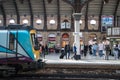 Transpennine Express train on a platform with York place name sign and people waiting on the platform