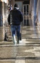 Transport cart and man with green boots at high tide