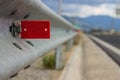 Transport highway infrastructure concept photography of red road reflector on metal side fence with unfocused background