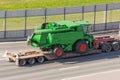Transportation of agricultural machinery harvester on a trailer of a truck loading platform on a highway in the city Royalty Free Stock Photo