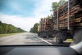 Transportation of forest logs on a truck trailer in summer on an asphalt road. Timber transportation, forest industry. Copy space