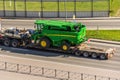 Transportation of harvester John Deere S760i loaded onto cargo platformon highway in the city. Russia, Saint-Petersburg. 22 may Royalty Free Stock Photo