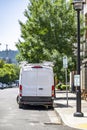 Transportation for small business compact mini van with ladders on the roof standing on the urban city street servicing customers