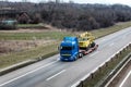 Transportation Tow truck or Flatbed truck on a highway carrying a construction machine