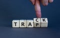 Trap or track symbol. Businessman turns wooden cubes and changes the word `trap` to `track`. Beautiful grey table, grey backgr