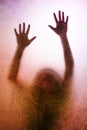 Trapped woman, back lit silhouette of hands behind matte glass