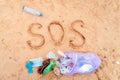 Trash bag with plastic bottles on a sandy beach. Text SOS on a sand. Top view. The concept of environmental protection Royalty Free Stock Photo