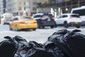 Trash bags with blurry traffic in background in urban environment with recycle concept.